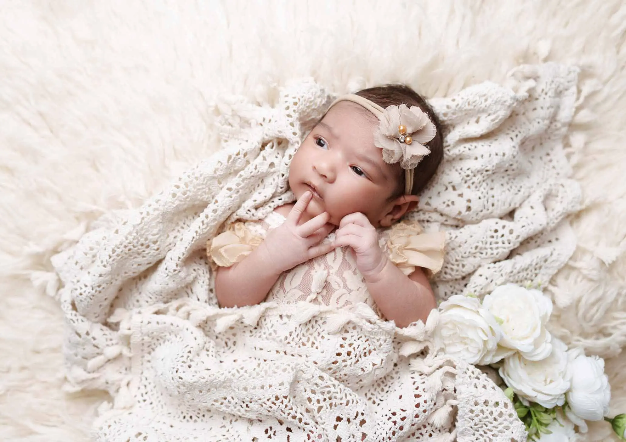 Newborn baby lying softly on cream blankets